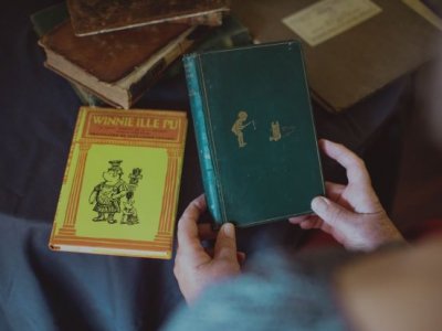 First edition Winne-the-Pooh being held with another book in background. Credit, UQ